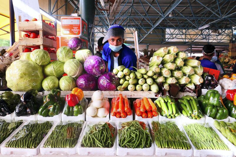 Shopkeeper wearing face mask and shield and selling vegetables at the Al Aweer fruit and vegetable market in Dubai on May 4,2021.  Pawan Singh / The National. 