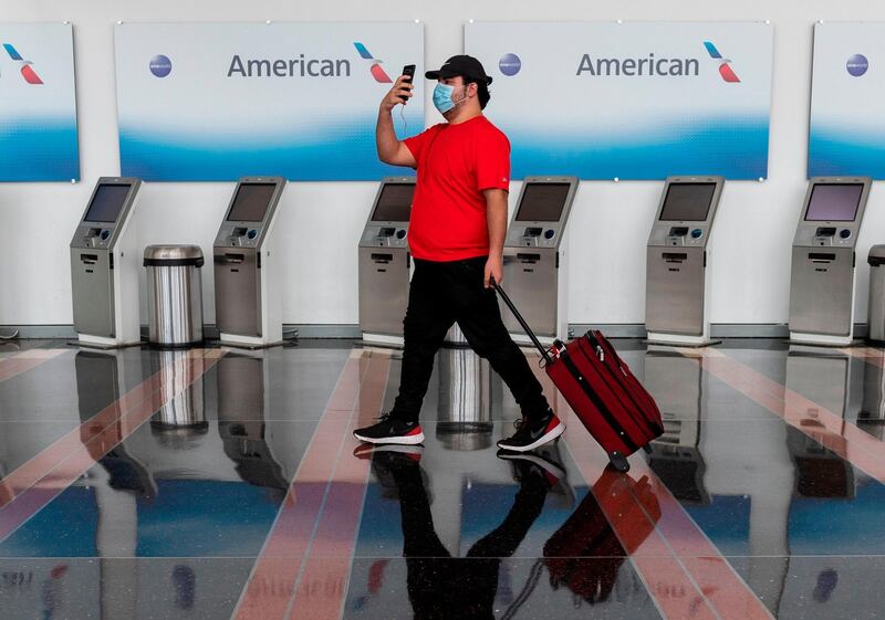 (FILES) In this file photo taken on May 12, 2020, a passenger walks past empty American Airlines check-in terminals at Ronald Reagan Washington National Airport in Arlington, Virginia. American Airlines is notifying 25,000 workers that they could be furloughed beginning October 1, although the number of layoffs may be minimized through voluntary programs, executives said on July 15, 2020. The major US carrier will have more than 20,000 more workers on payroll than needed due to a profound downturn in business caused by the coronavirus pandemic, Chief Executive Doug Parker and President Robert Isom said in a memo to employees. / AFP / ANDREW CABALLERO-REYNOLDS
