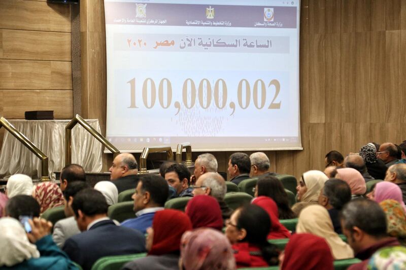 People sit near a screen displaying the population count at the Egyptian Ministry of Planning, in Cairo, Egypt. EPA