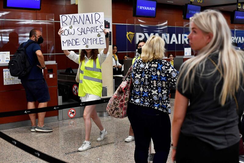 A woman holds a placard reading 'Ryanair, low salaries made simple' as she protests at El Prat airport in Barcelona. AFP