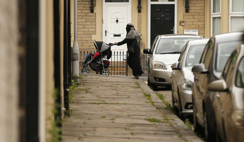 A muslim woman pushes a pram along a road in Bradford, Britain. A new report of the state of community relations highlighted disturbing levels of segregation, deprivation and social exclusion. REUTERS/Phil Noble - RTX1H9SC