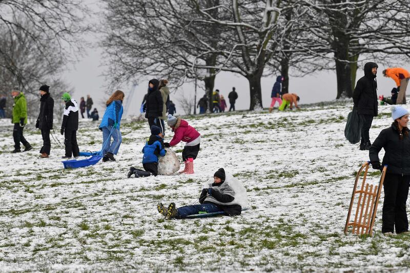 People play in the snow on Primrose Hill in London, as the capital experiences a rare covering of snow on Sunday. AFP