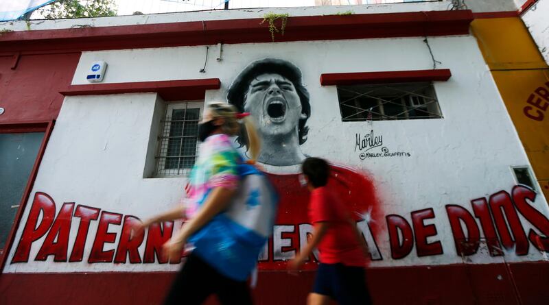 A woman and a boy walk past a mural of Diego Maradona in Buenos Aires. Getty
