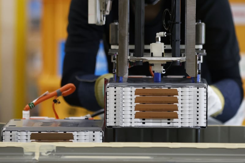 A worker installs a stack of lithium-ion batteries onto a battery pack for a kei electric vehicle. Bloomberg