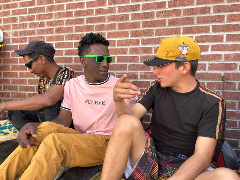 Paolo, 21, on the right, sits with other migrants outside the Sacred Heart Church in El Paso