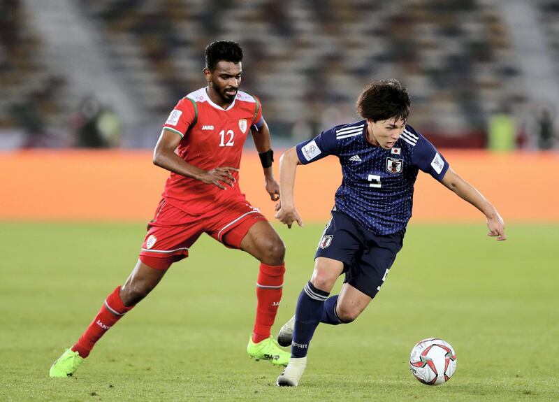 Abu Dhabi, United Arab Emirates - January 13, 2019: Minamino Takumi of Japan and Ahmed Al Mahaijri of Oman battle during the game between Japan and Oman in the Asian Cup 2019. Sunday, January 13th, 2019 at Zayed Sports City Stadium, Abu Dhabi. Chris Whiteoak/The National