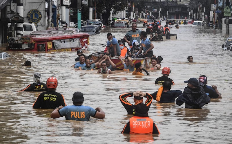 Rescuers pull a rubber boat carrying residents through a flooded street after Typhoon Vamco hit in Marikina. AFP