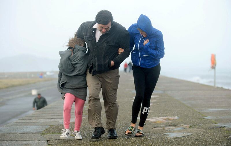 A family walks along a sea wall during storm Ophelia on East Pier in Howth, Dublin, Ireland. Caroline Quinn / PA via AP