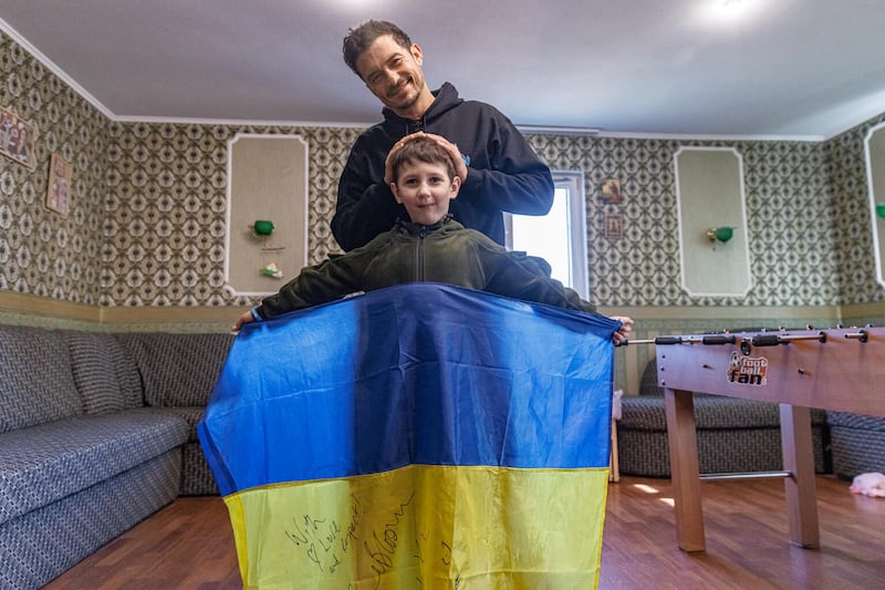 Bloom poses with Yehor, 8, holding a Ukrainian flag signed by the actor, in Demydiv, Ukraine. Reuters