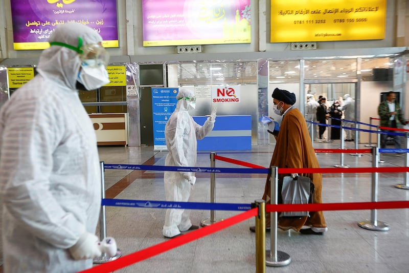 A medical staff member in protective gear prepares to check the temperature of a cleric man amid concerns over the coronavirus (COVID-19) spread, at Najaf airport in the holy city of Najaf upon his arrival from Iran, Iraq. REUTERS