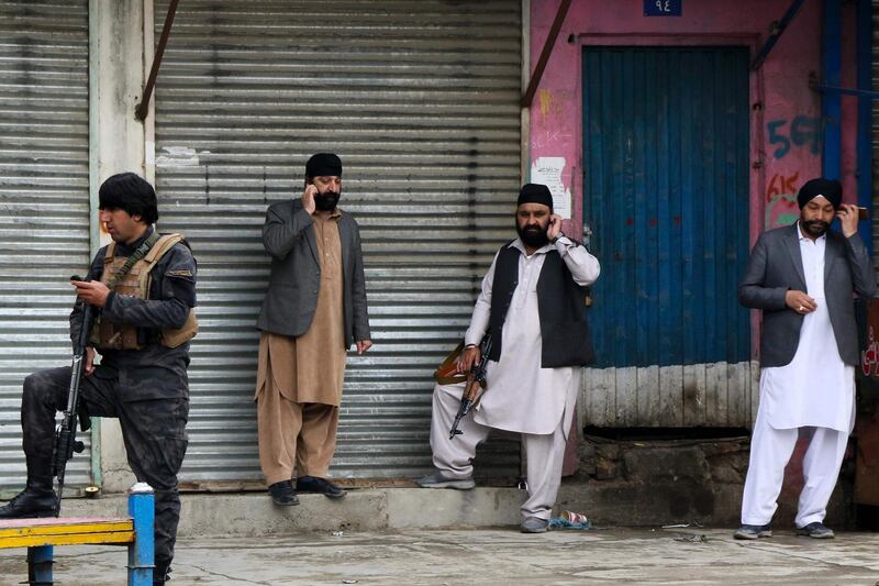 An Afghan security personnel (L) stands along with Sikhs near the site of an attack to a Sikh temple in Kabul.  AFP