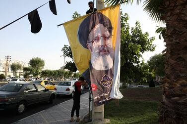 Two workers hang a banner of the presidential candidate Ebrahim Raisi, currently judiciary chief, near his campaign rally in town of Eslamshahr southwest of the capital Tehran, Iran. AP