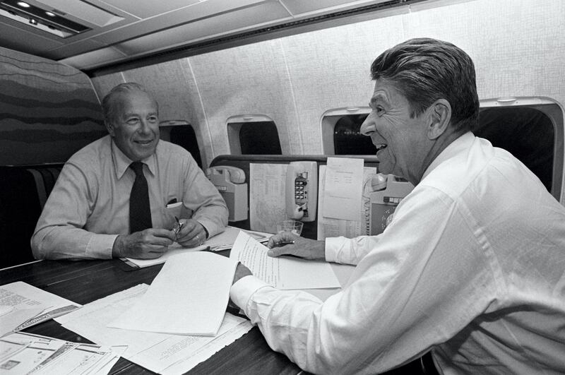 (Original Caption) Pittsburgh, PA: Republican presidential candidate Ronald Reagan and former secy. of the treasury George Shultz do some work on plane while enroute to Pittsburgh from Wilkes-Barre, Pa. Shultz is serving as a senior advisor to Reagan.