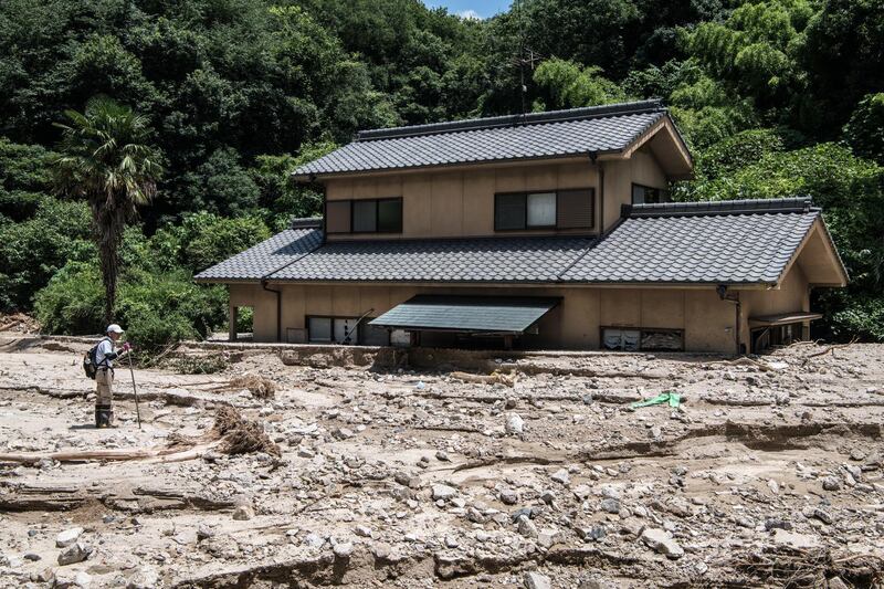 A man searches for his missing son next to a house submerged in mud after discovering his car nearby in Yanohigashi, Japan, on July 10, 2018. Getty Images