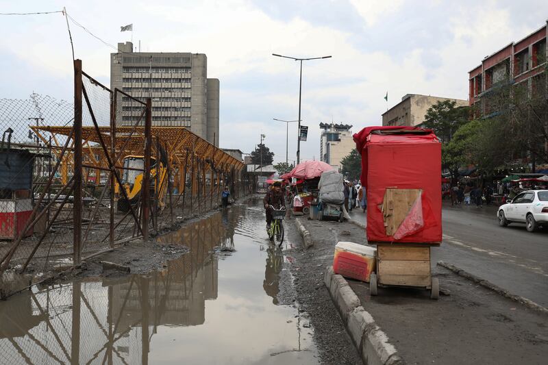 An Afghan man rides his bicycle on a waterlogged street on a rainy day in Kabul