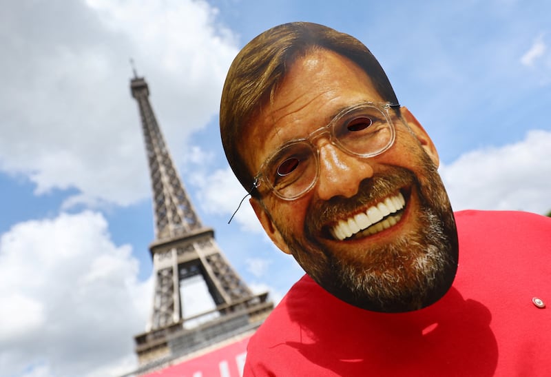 A Liverpool fan wears a mask of manager Jurgen Klopp in front of the Eiffel Tower. Reuters