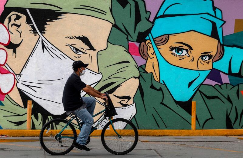 A man rides past a coronavirus-related mural by urban artists Mick Martinez and "Were Torres" in Ciudad Juarez, Chihuahua state, Mexico. AFP