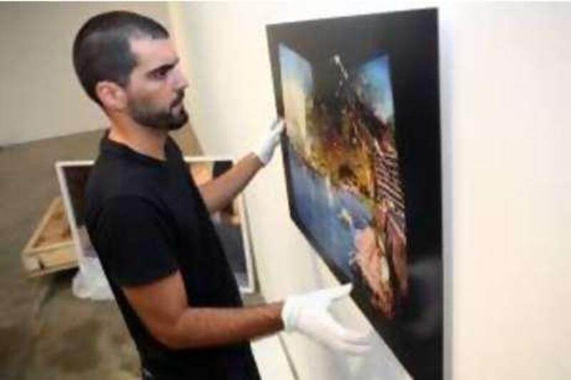 Dubai, UAE - August 28, 2008 - Haig Aivazian, Artist Liaison and Exhibitions Director for The Third Line gallery hangs works by artists Fouad Elkhoury, Joana and Khalil. (Nicole Hill / The National) *** Local Caption ***  NHThirdLine3.jpg