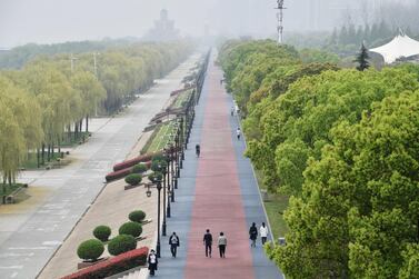 People wearing face masks walk at a riverside park in Wuhan of Hubei province. Reuters