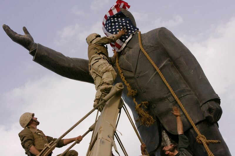 A US Marine uses an American flag to cover the face of a statue of Saddam Hussein before pulling the monument down in Baghdad on April 9, 2003. AP