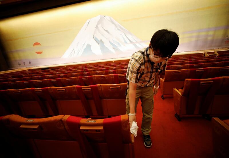 A member of staff wearing a protective mask disinfects a seat at the Kabukiza Theatre. Reuters
