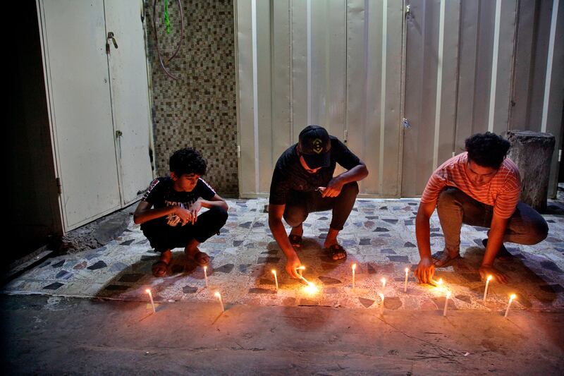 People light candles at the site of a bombing in Wahailat market in Sadr City, Iraq.
