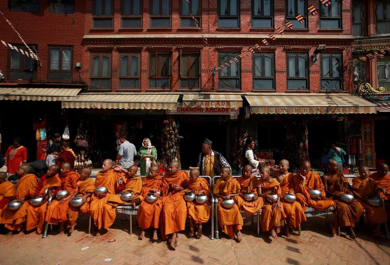 Buddhist monks wait to receive alms during the birth anniversary of Buddha, also known as Vesak Day, at Boudhanath Stupa in Kathmandu, Nepal.  Reuters