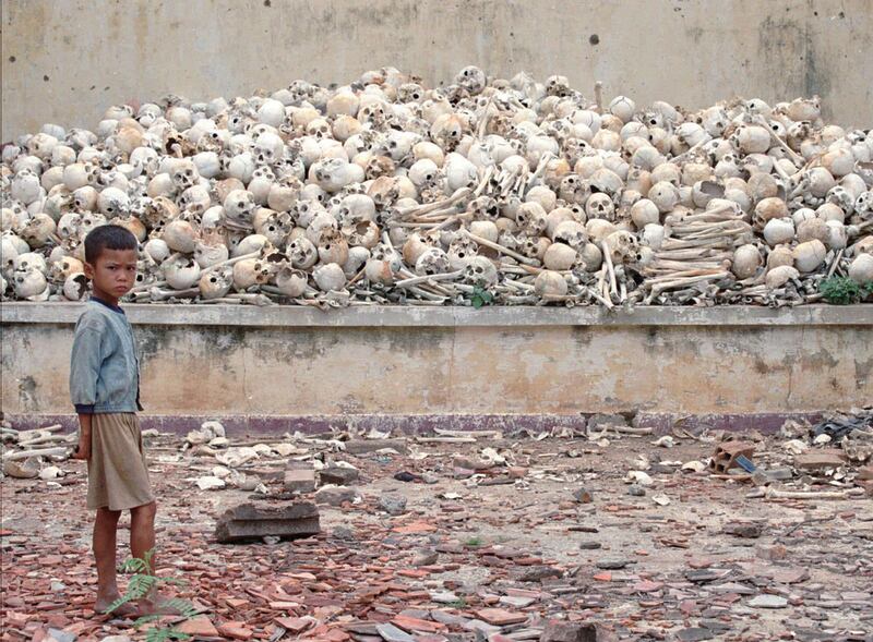 A Cambodian boy stands in front of a platform covered with human skulls at a killing field discovered in Trapeang Sva Village in 1995. AP Photo / Richard Vogel