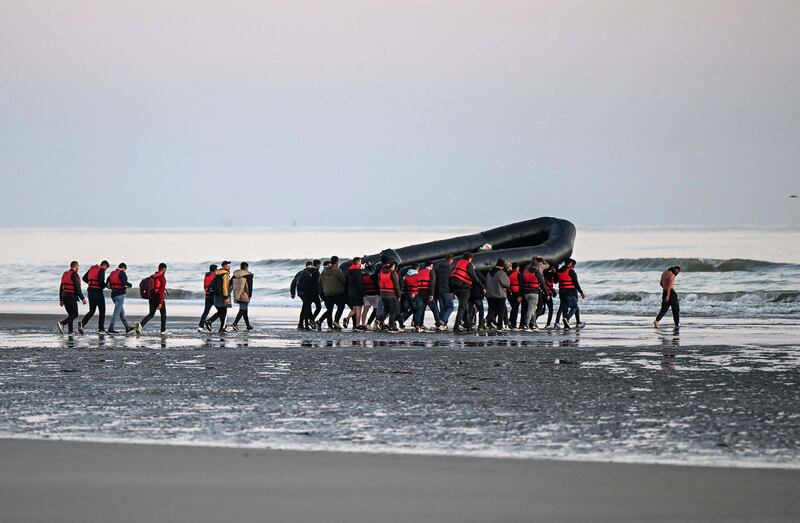 Migrants carry an inflatable boat as they attempt to cross the English Channel illegally to the UK from France. Almost 700 migrants and asylum seekers crossed the Channel to Britain in a single day last week, a new record for the year, the UK government said on August 2. AFP