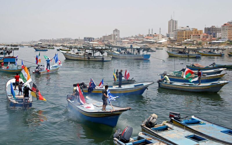 Palestinians ride boats with flags during an event to show solidarity with countries affected by the coronavirus disease . Reuters