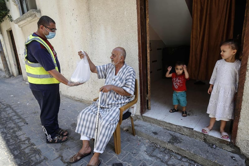 Palestinian volunteers distribute food to empoverished people in Rafah in the southern Gaza Strip during a lockdown in the Palestinian enclave due to increasing cases of the Covid-19 coronavirus infections.  AFP