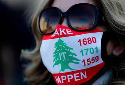 An activist wears a mask to protect from COVID-19, with the colors of the Lebanese flag and the U.N. Resolutions numbers that called for disarmament all Lebanese and non-Lebanese militias, during a sit-in to mark the 47th anniversary of the 1975-90 Civil War, in Beirut, Lebanon, Tuesday, April 13, 2021. The 15-year Civil War began on April 13, 1975 and killed more than 150,000 people. (AP Photo/Hussein Malla)