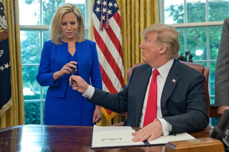 FILE - In this Wednesday, June 20, 2018 file photo, President Donald Trump gives the pen he used to sign the executive order to end family separations to Homeland Security Secretary Kirstjen Nielsen, left, during an event in the Oval Office of the White House in Washington. On Saturday, Dec. 29, 2018, the president deflected any blame from his administration for the deaths of two Guatemalan children in December in U.S. government custody as his Homeland Security adviser visited Border Patrol medical officials amid promises of more thorough health screenings for migrant children. (AP Photo/Pablo Martinez Monsivais)