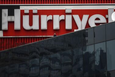 This picture taken on March 22,2018 shows a man standing beneath the Hurriyet newspaper's logo at the Dogan media group complex in Istanbul. Ozan Kose / AFP Photo