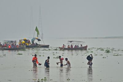 People wade through flood waters after monsoon rains in Prayagraj. AFP