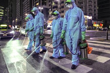 Workers from Tadweer, the Abu Centre for Waste Management, spraying the streets of Abu Dhabi during the disinfection drive in March as the pandemic hit. Victor Besa / The National 