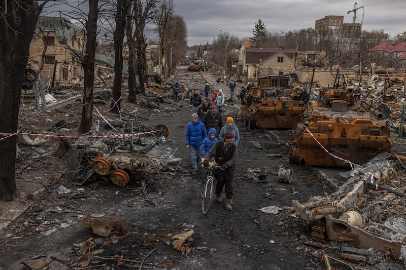 Residents walk past destroyed Russian military machinery on the street, in Bucha, the town which was retaken by the Ukrainian army, north-west of Kyiv. EPA