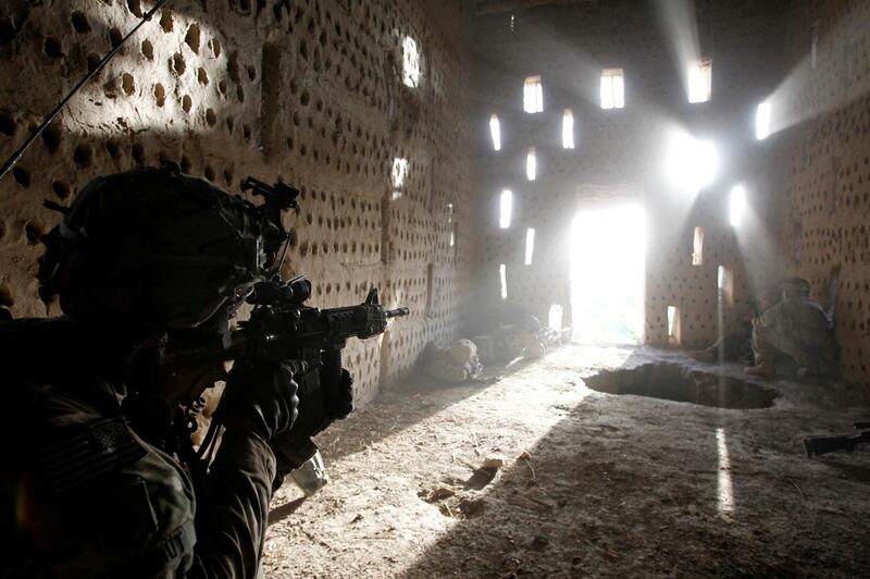 US soldier Nicholas Dickhut, from 5-20 infantry Regiment, attached to 82nd Airborne, points his rifle at a doorway after coming under fire by the Taliban while on patrol in Zharay district in Kandahar province, Afghanistan April 26, 2012. Reuters