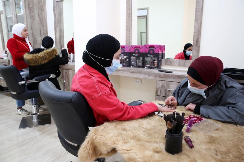 Palestinian henna tattoo artist Samah Sidr draws a henna tattoo on a girl's hand, at her shop in Hebron, to mark International Women's Day. The annual global event celebrates the social, economic, cultural, and political achievements of women. EPA