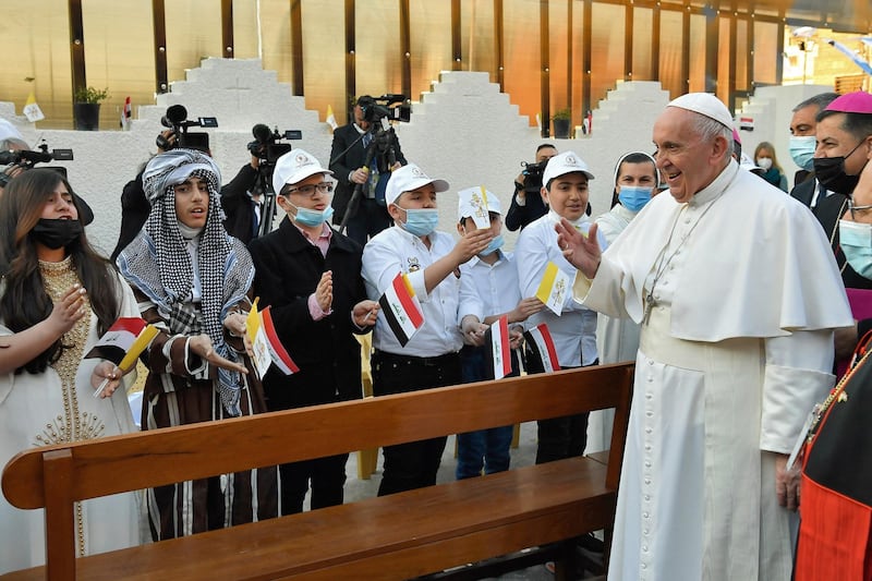 Pope Francis greeted by children upon his arrival for a mass at Baghdad's Saint Joseph Cathedral. AFP