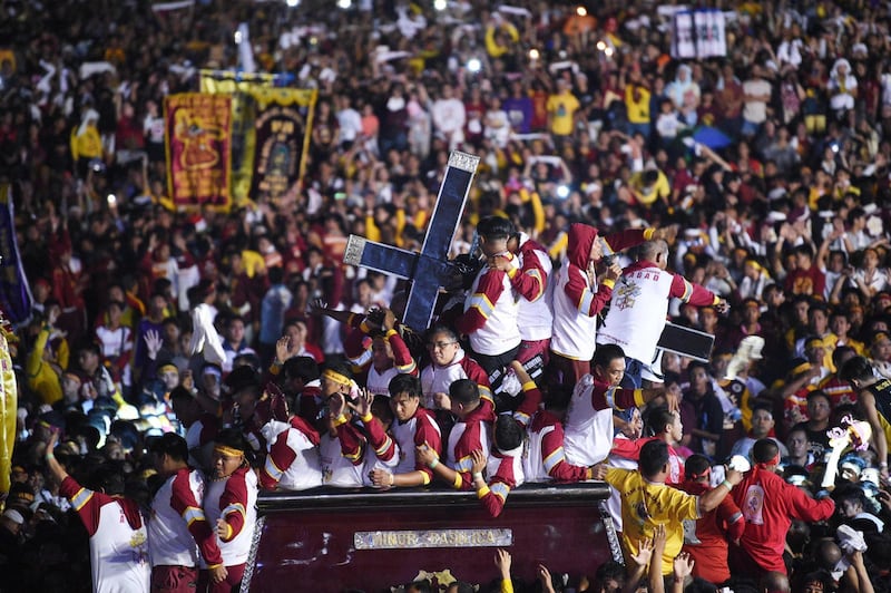 Catholic devotees suround the statue of the Black Nazarene on a carriage during the annual religious procession. AFP