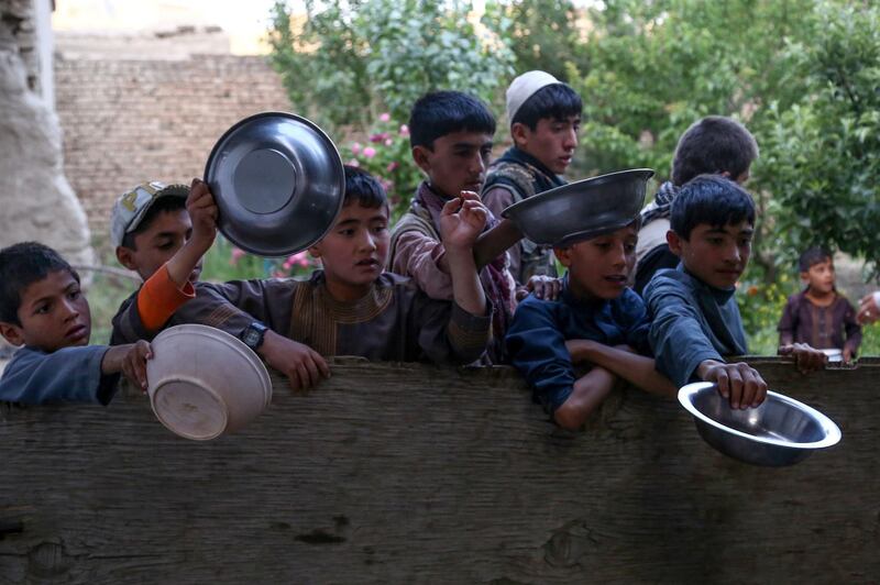 Afghan children hold plates out as they wait to receive food donated by a private charity during Ramadan in Ghazni Province. AFP