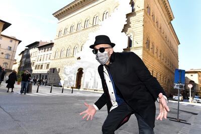 French contemporary artist JR poses in front of his art installation on the facade of Strozzi Palace titled 'La Ferita (The Wound)', and showing an optical illusion of a black and white interior of the elegant Renaissance palace, as the artist's efforts to make a statement on accessibility to culture in the coronavirus disease (COVID-19) era, in Florence, Italy, March 19, 2021. REUTERS/Jennifer Lorenzini