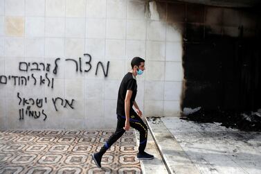 A Palestinian man walks past Hebrew graffiti that says: “A siege for Arabs, not for Jews! the Land of Israel for the People of Israel” after a mosque section was set on fire, in Al Bireh in the Israeli-occupied West Bank. Reuters