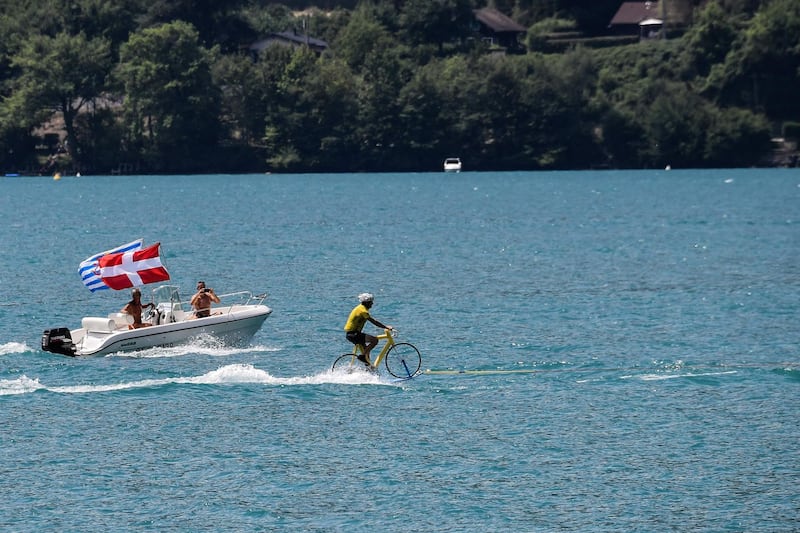 A man wearing a yellow jersey performs water skiing on a bicycle, on the Lake of Annecy during the 10th stage of the Tour de France between Annecy and Le Grand-Bornand. Jeff Pachoud / AFP