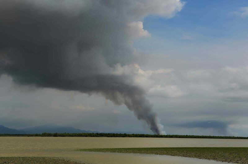 (FILES) In this file photo taken on September 14, 2017 smoke is seen billowing in an area inland in Myanmar's Rakhine state as seen from the Bangladeshi shore of the Naf river near Teknaf. Some 200,000 Rohingya rallied in a Bangladesh refugee camp on August 25, 2019 to mark two years since they fled a violent crackdown by Myanmar forces, just days after a second failed attempt to repatriate the refugees. / AFP / MUNIR UZ ZAMAN
