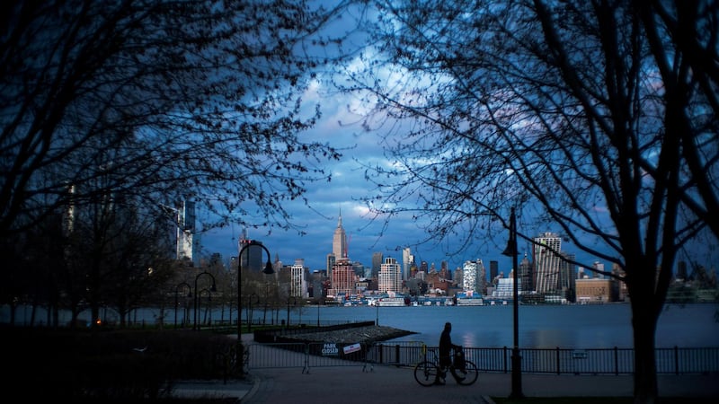 A man pushes his bike in a closed park as the New York City skyline are seen during the outbreak of the coronavirus disease in New York City, as seen from Weehawken, New Jersey. Reuters