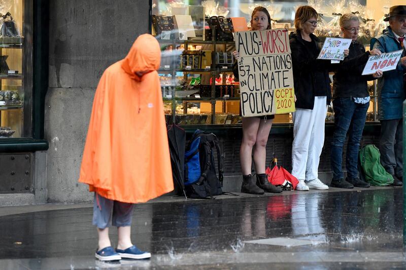 Climate change protestors are seen shielding themselves from the heavy rain in Sydney's central business district, New South Wales, Australia.  EPA