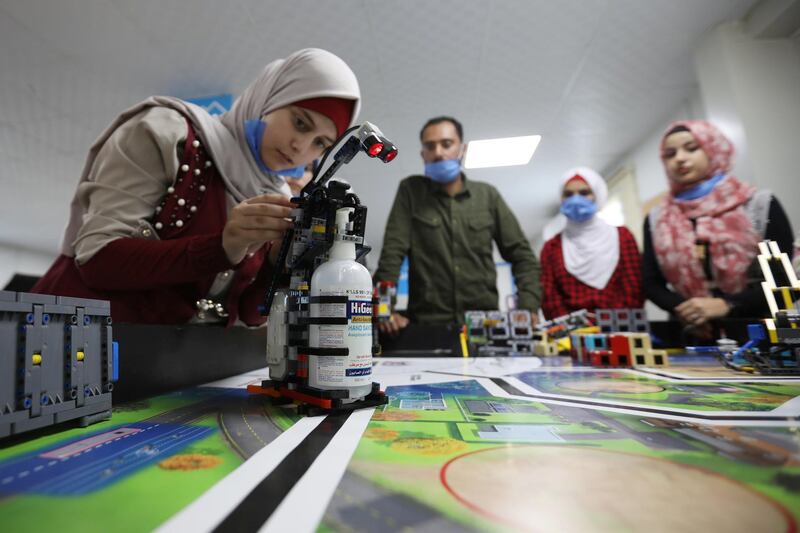 Syrian refugee students and instructor, Yasine Hariri, use his invention that is a robot prototype that automatically dispenses sanitiser to avoid contact and combat the spread of the coronavirus disease (COVID-19) as a part of the camp's UNHCR-led Innovation Lab program, at the Zaatari refugee camp in the Jordanian city of Mafraq, near the border with Syria. REUTERS