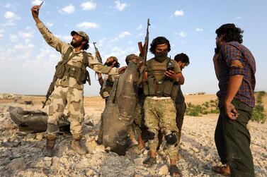 Rebel fighters pose for a picture with the remains of a downed regime warplane near the militant-held town of Khan Sheikhun in the south of Idlib province. AFP